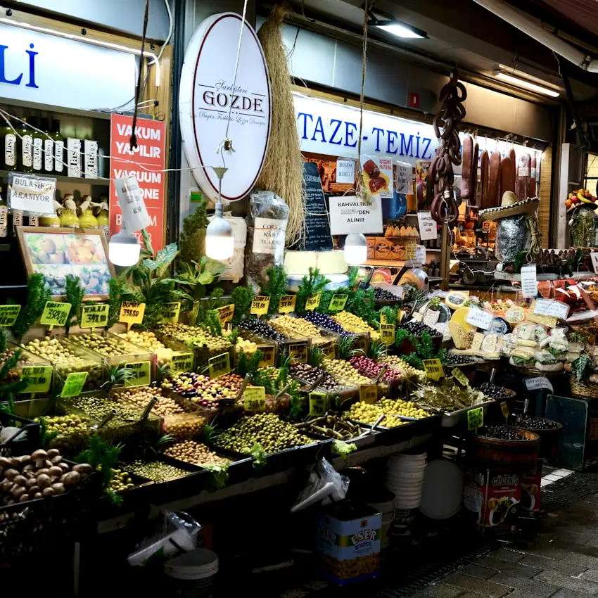 Ein Marktstand mit Kräuterbündeln, Oliven und eingelegtem Gemüse.