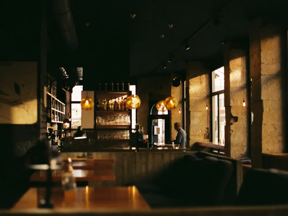 Ein abendlicher Gastraum im Gegenlicht, Tische im Halbdunkel.