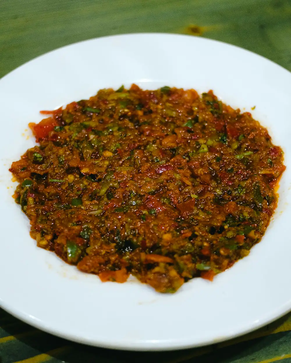 Fein geschnittene Paprika-Tomaten-Paste, flach auf einem weißen Teller ausgestrichen.