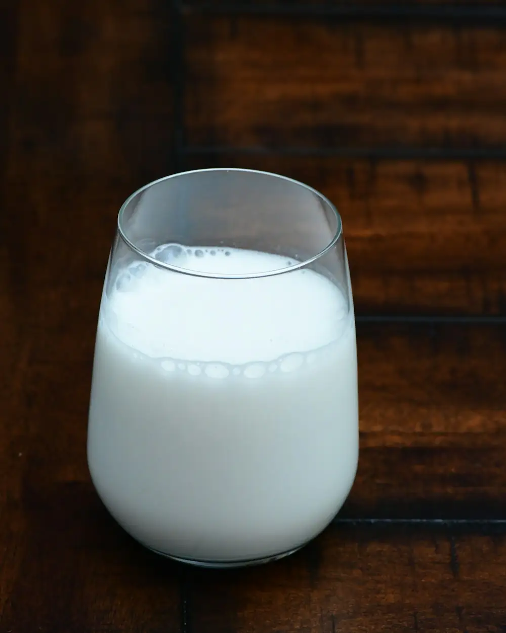 Ein Glas gekühlter Ayran auf dunklem Holz.
