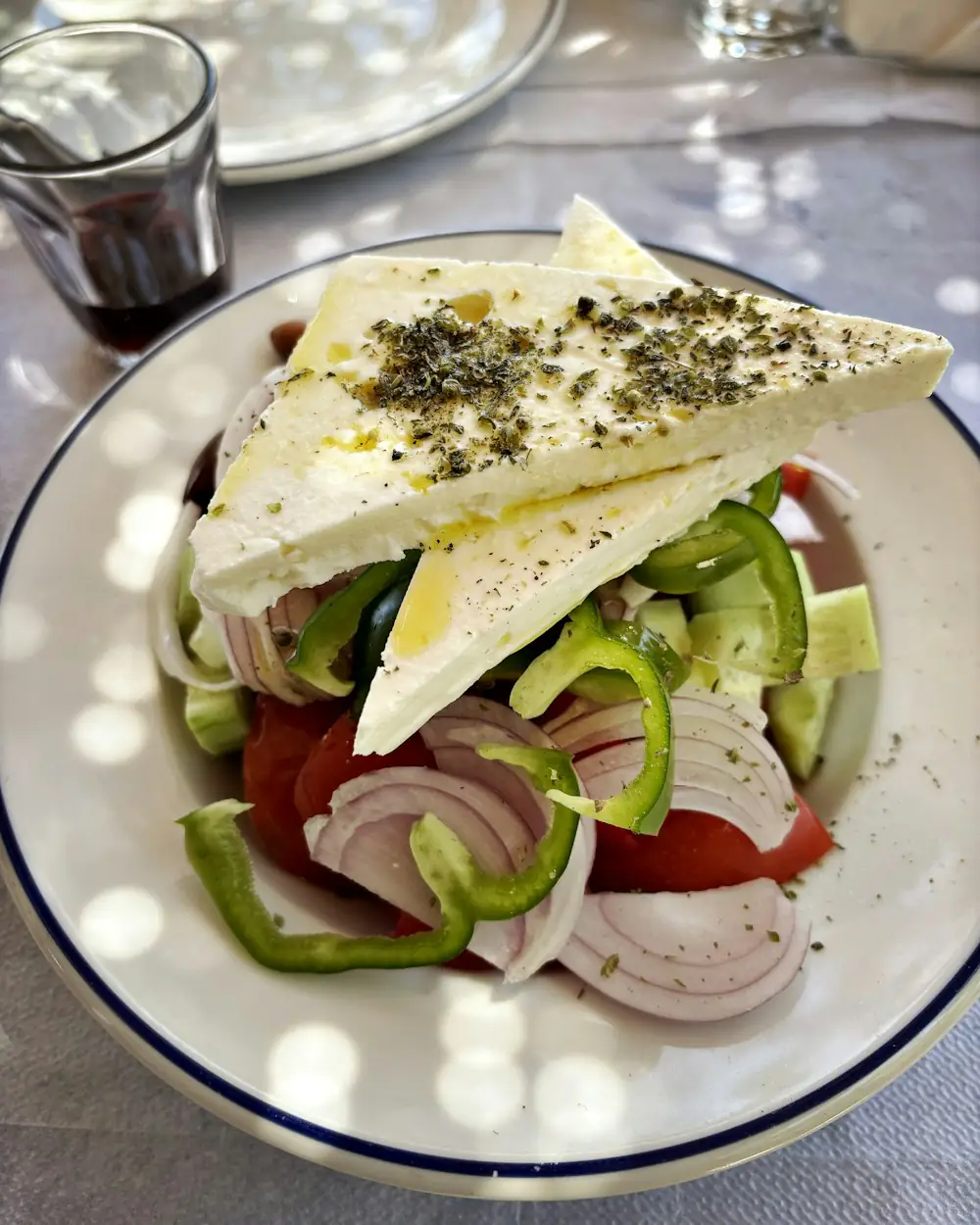 Tomaten, Gurke, Paprika und Zwiebeln mit Weißkäse auf einem Teller.