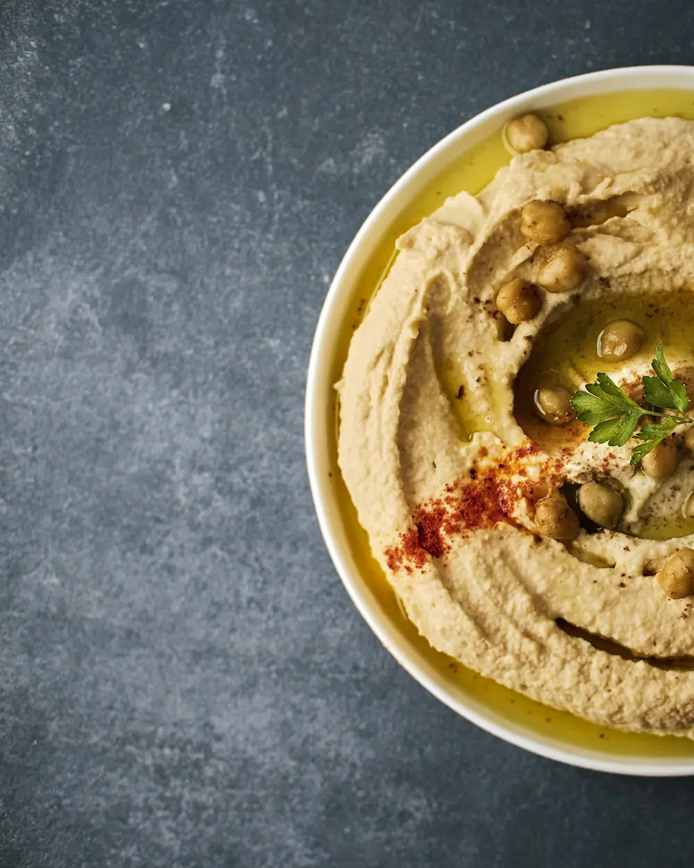 Cremiger Hummus in einer Schale, mit Olivenöl und Paprikapulver bestreut.