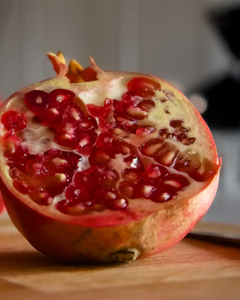 Ein aufgeschnittener Granatapfel auf einem Holzbrett.