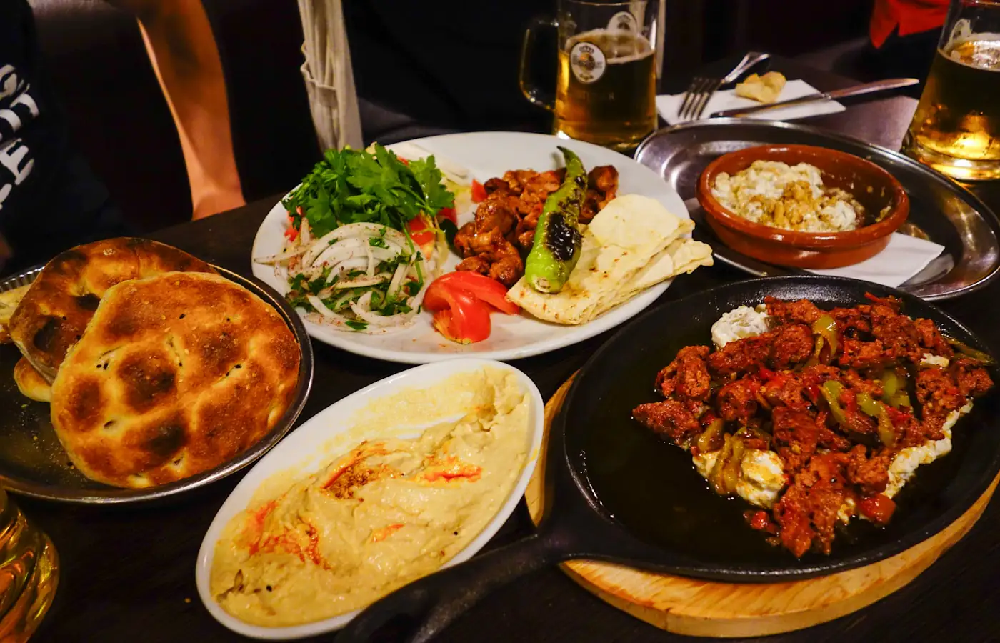 Ein voll gedeckter Tisch mit Fladenbrot, Dips und mehreren kleinen Gerichten zum Teilen.